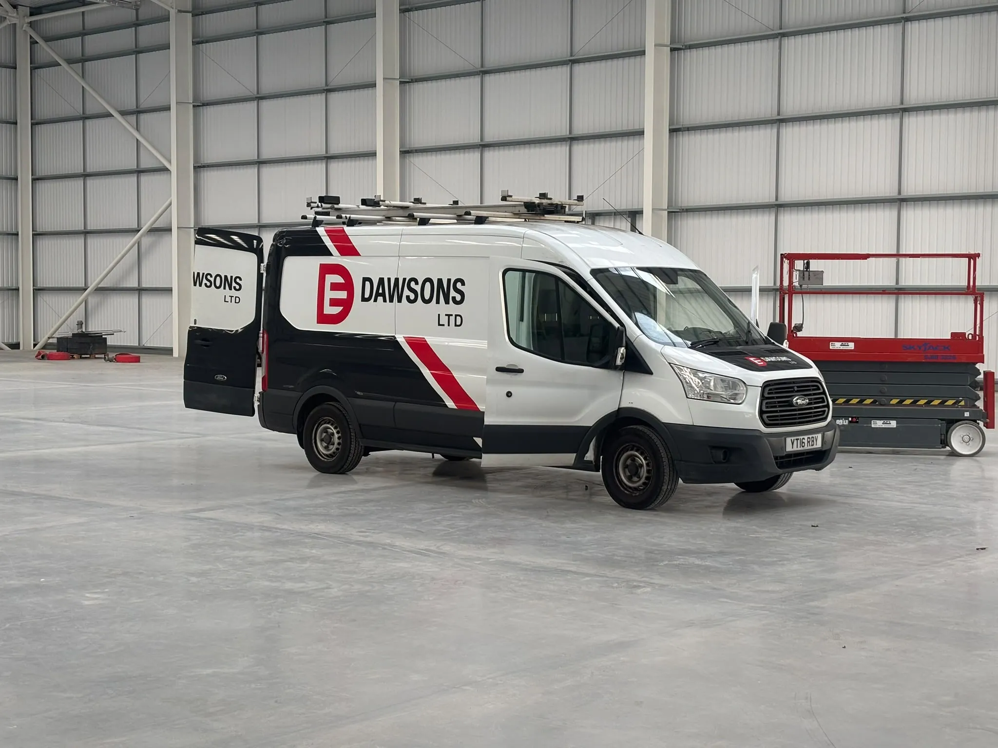 A Dawsons Ltd van parked inside an empty commercial unit alongside a scissor lift